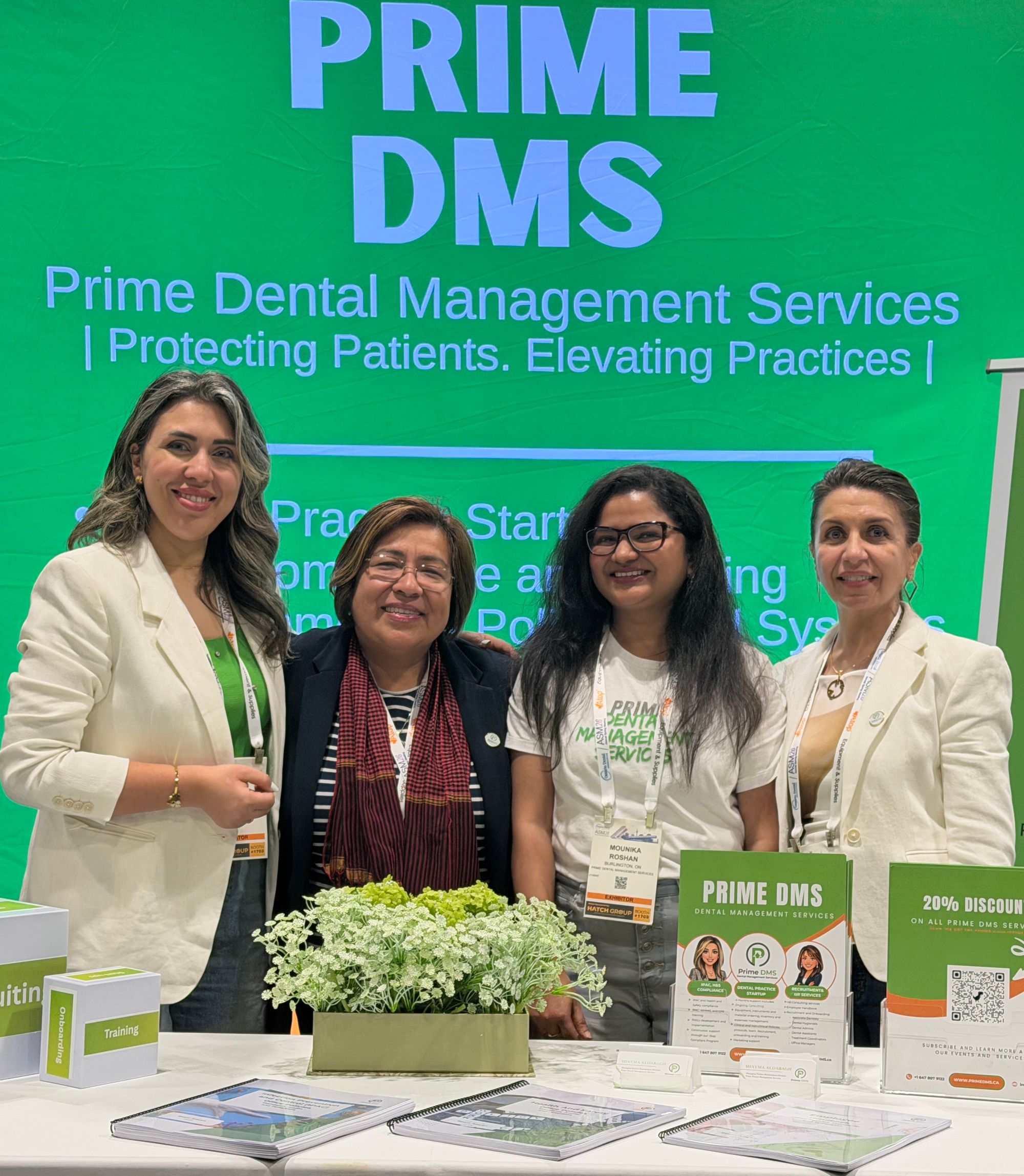Prime Dental Management Services team at a trade show in front of the Prime DMS green banner